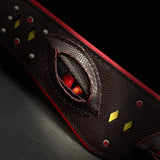 Macro of the Blood Dragon Collar: red dragon eye with slit pupil under layered snake-embossed leather eyelids, dark red scales, yellow diamond inlays, red crystals, silver studs and red lining